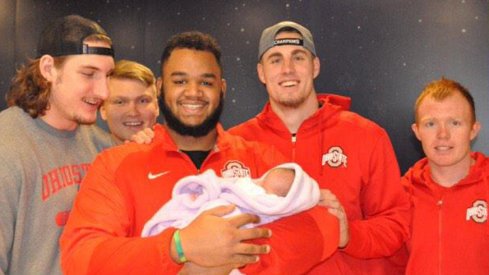 Ohio State All-American defensive tackle Michael Bennett holds a three-week-old baby, Bayah, at Nationwide Chilrden's Hospital Friday.