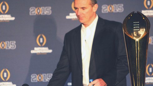 Urban Meyer standing next to the National Championship trophy