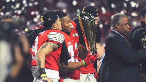 Devin Smith (left) and Darron Lee (right) spend time with the CFP trophy.