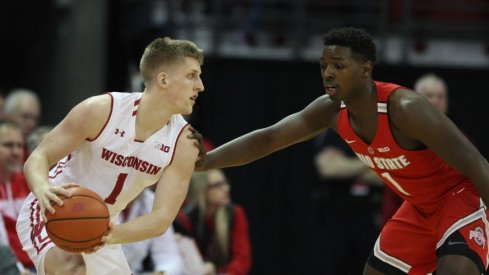 Ohio State basketball player Jae'Sean Tate guards a Wisconsin player