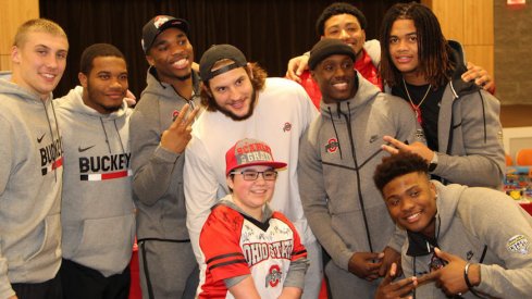 Tuf Borland, J.K. Dobbins, Jeffrey Okudah, Nick Bosa, Demario McCall, Malik Harrison, Chase Young and Dwayne Haskins take a picture with Nationwide Children's Hospital patient Rayne McCann.