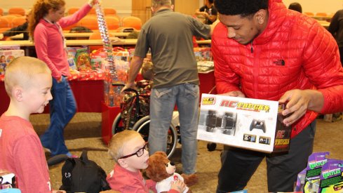 Malik Harrison helps a child pick out a toy during the Buckeyes' visit to the Nationwide Children's Hospital on Monday.