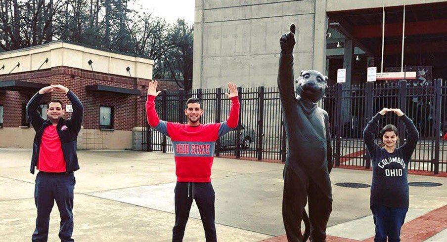 Ohio State student Corey Greenblat strikes the O–H–I–O pose with the Clemson tiger statue.